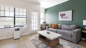 A living room with a grey sofa, a white coffee table, and a green accent wall. - Landing | Spectacular 2BD, Gym (Garland)