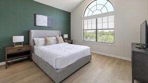 A bedroom with a bed, nightstands, a lamp, a TV, a window with blinds, and a painting on the wall. - Landing | Stylish 2BD, Gym (Garland)