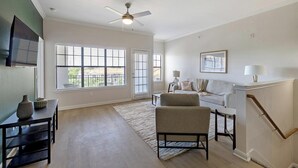 A spacious living room with a sofa, a coffee table, and a TV mounted on the wall. - Landing | Stylish 2BD, Gym (Garland)