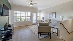 A spacious living room with a sofa, a coffee table, and a TV mounted on the wall. - Landing | Spectacular 2BD, Gym (Garland)