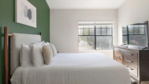 Ein Schlafzimmer mit Bett, Kommode, Fenster und einem Bild an der Wand.
