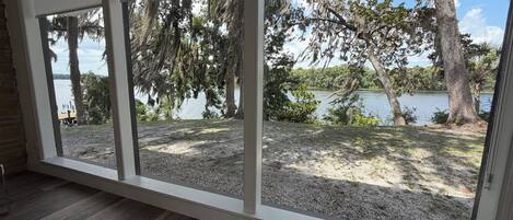 A room with large windows offering a view of a lake, trees, and a dock.