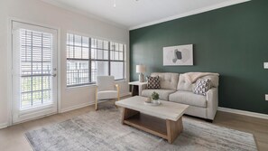 A living room with a sofa, a coffee table, a chair, and a lamp. - Landing | Amazing 2BD, Gym (Garland)