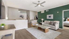 Een moderne woonkamer met een bank, salontafel en een plafondventilator.