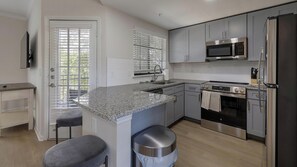 A modern kitchen with granite countertops, stainless steel appliances, and a built-in oven. - Landing | Stylish 2BD, Gym (Garland)