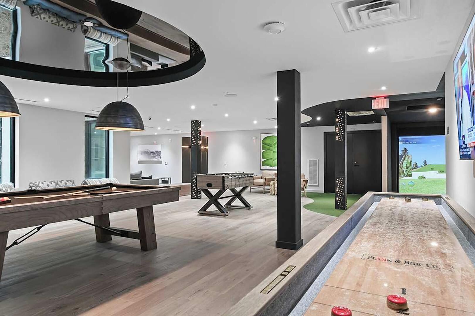 Un espace piscine intérieur moderne, équipé d’une table de billard, d’un baby-foot et d’un grand écran.