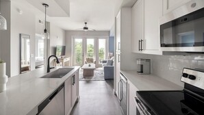 Une cuisine moderne dotée d’un grand îlot central, d’appareils électroménagers intégrés et offrant une vue sur l’espace de vie.
