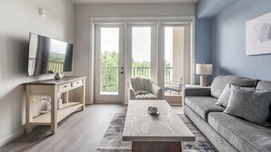 Un salon moderne avec un téléviseur à écran plat, un canapé, une table basse et un fauteuil.