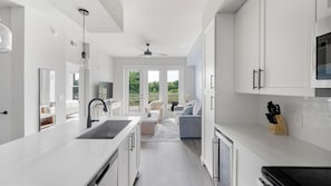 A modern kitchen with white cabinetry, a built-in stove, and a large window overlooking a balcony. - Landing | Chic 1BD in Cool Springs (Franklin)