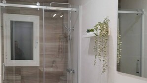 A modern bathroom with a glass-enclosed shower, a white toilet, a wooden vanity, and a mirror. - Room-modern Comfort in Madrid Premium Ro (Madrid)