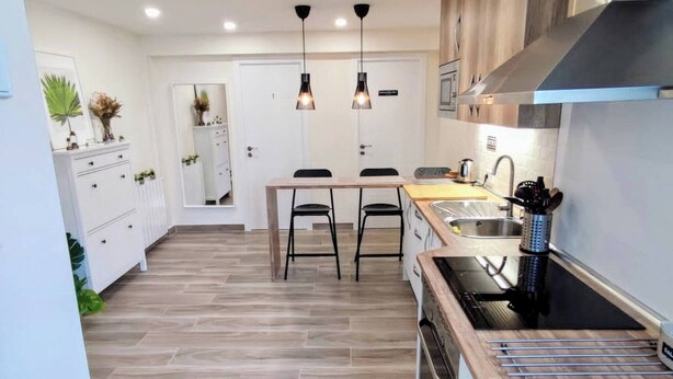 A modern kitchen with a central island, pendant lights, and a stainless steel range hood. - Room-modern Comfort in Madrid Premium Ro (Madrid)