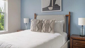 Ein Schlafzimmer mit einem Bett, zwei Nachttischen, einer Lampe und einem Bild an der Wand.