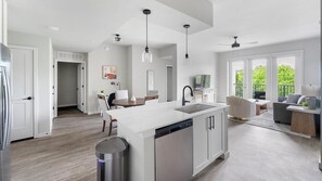 Eine moderne Küche mit einer zentralen Kochinsel, einem Essbereich und einem Balkon mit Gartenmöbeln.