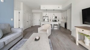 A modern living room with a grey sofa, a coffee table, and a TV on a stand. - Landing | Stylish 2BD in Cool Springs (Franklin)
