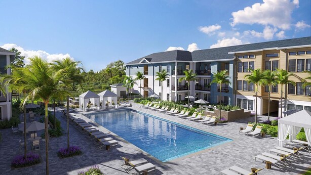 Ein modernes Hotel mit einem zentral gelegenen Schwimmbad, Lounges und Palmen.