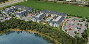 Eine Vogelperspektive eines Hotelkomplexes mit mehreren Gebäuden, einem Swimmingpool und einem Parkplatz.