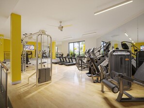 Ein Fitnessstudio mit Cardiogeräten, Gewichte und einem Deckenventilator.