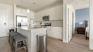 Una cocina moderna con armarios blancos, electrodomésticos de acero inoxidable y una isla central.