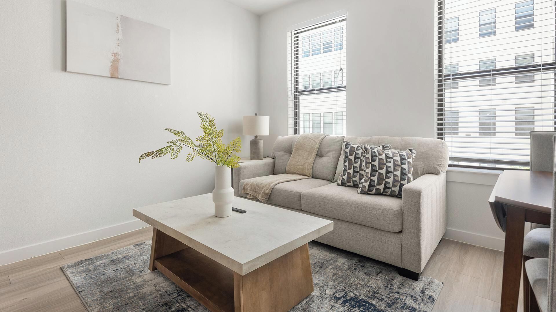 A modern living room with a sofa, a coffee table, a lamp, and a plant.