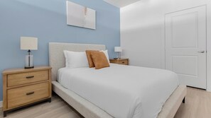 Ein Schlafzimmer mit einem Bett, zwei Nachttischen, einer Ablage und einem an der Wand hängenden Kunstwerk.