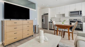 Eine moderne Küche mit weißen Schränken, einem Edelstahlkühlschrank, einer Mikrowelle und einem Backofen.