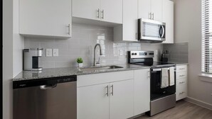 Une cuisine moderne avec des armoires blanches, un four à micro-ondes encastré, un lave-vaisselle et une cuisinière.