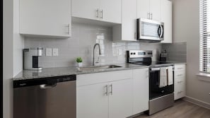 A modern kitchen with white cabinets, a built-in microwave, a dishwasher, and a stove. - Landing | Stunning 1BD, Pool, Gym (Austin)