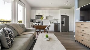 Eine moderne Wohnung mit Wohnzimmer, Essbereich, Küche und Fernseher.