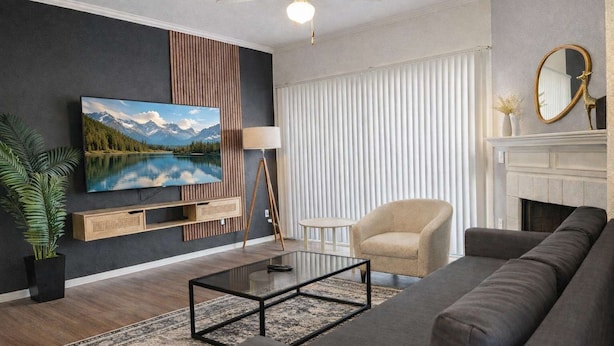 Ein modernes Wohnzimmer mit Flachbildfernseher, Kamin, Sofa und Couchtisch.