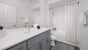 Ein modernes Badezimmer mit einem Doppelwaschbecken, einer Badewanne und einer Toilette.