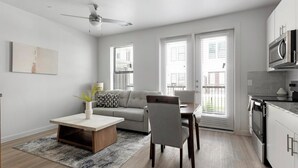 A modern apartment with a dining area, sofa, kitchen, and large windows. - Landing | Modern 1BD, Gym, Pool (Austin)
