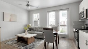 A modern apartment with a dining area, sofa, kitchen, and large windows. - Landing | Stunning 1BD, Pool, Gym (Austin)
