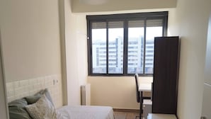 Un dormitorio con cama, escritorio y armario.