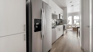 Eine moderne Küche mit Edelstahlgeräten, weißen Schränken und Holzboden.