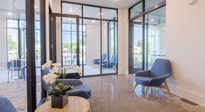 A modern interior with a seating area, large windows, and a potted plant. - Landing | Beautiful Studio, Pool, Gym (Austin)