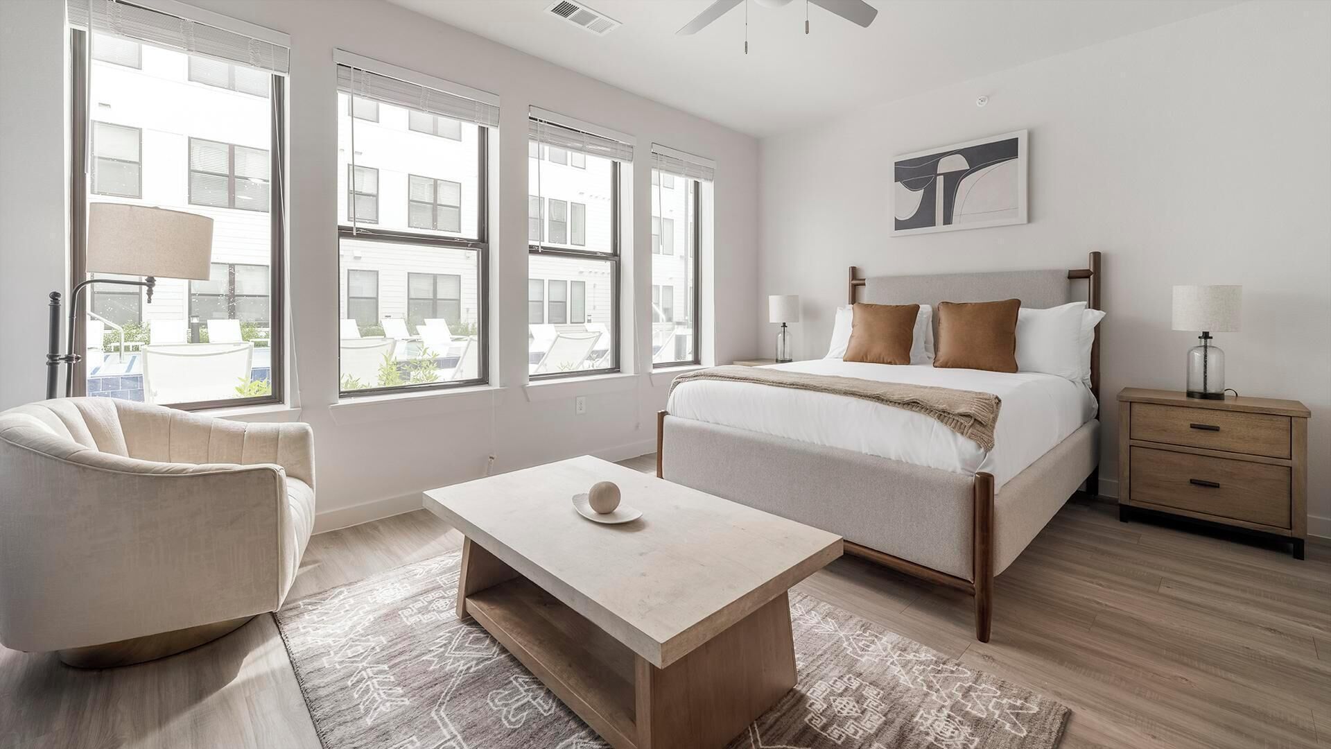 Une chambre à coucher avec un lit, des tables de chevet, une chaise et une fenêtre avec des stores.