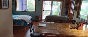 Ein Zimmer mit zwei Betten, einem Esstisch, Stühlen, einem Fenster mit Blick und einer Tür.