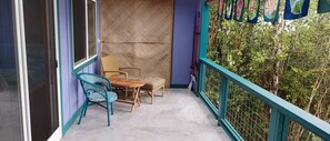 Ein Balkon mit Korbmöbeln, einem Tisch und Stühlen mit Blick auf eine üppige Grünfläche.