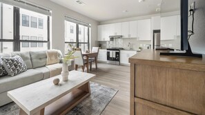 Eine moderne Küche mit weißen Schränken, einer Holztischinsel und einem Essbereich mit Sofa und Couchtisch.