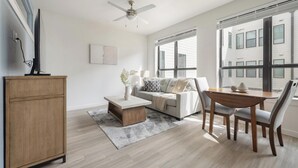 A modern living room with a sofa, coffee table, dining table, and chairs. - Landing | Amazing 1BD, Pool, Gym (Austin)