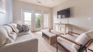 A living room with a sofa, a coffee table, a TV, and a desk.
