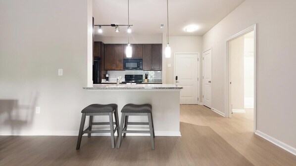 A modern kitchen with dark wood cabinets, a central island with stools, and pendant lighting.