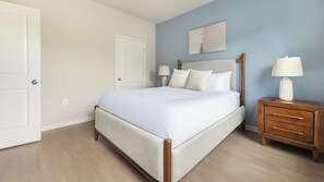 A bedroom with a bed, bedside tables, and a door. - Landing | Amazing 1BD, Pool, Gym (Manassas Park)