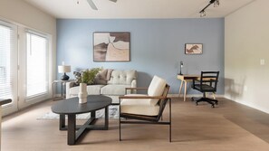 Una sala de estar moderna con sofá, sillón, mesa de centro y escritorio con silla.