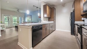 A modern kitchen with a central island, built-in appliances, and a dining area with a view.