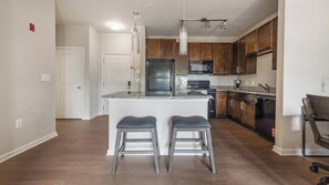 A modern kitchen with a central island, stainless steel appliances, and wooden cabinets.