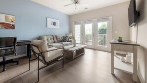 A modern living room with a sofa, coffee table, and a desk with a chair.