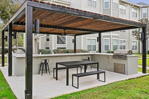 An outdoor patio with a grill, seating, and a pergola structure. - Landing | Stylish 2BD, Yoga Studio, Gym (Humble)