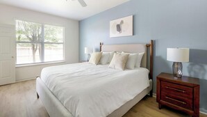 Een slaapkamer met een bed, nachtkastjes, een raam en een aan de muur hangend schilderij.