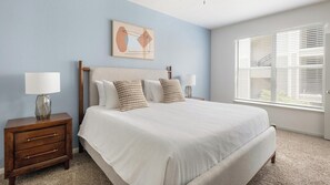 A bedroom with a bed, nightstands, a lamp, a window, and a wall art piece. - Landing | Modern 2BD, Pool, Yoga Studio (Humble)